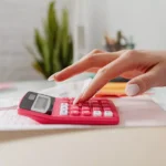 Pessoa utilizando uma calculadora para analisar despesas e renda durante a avaliação financeira do Jobseeker’s Allowance na Irlanda.