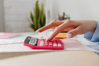 Pessoa utilizando uma calculadora para analisar despesas e renda durante a avaliação financeira do Jobseeker’s Allowance na Irlanda.