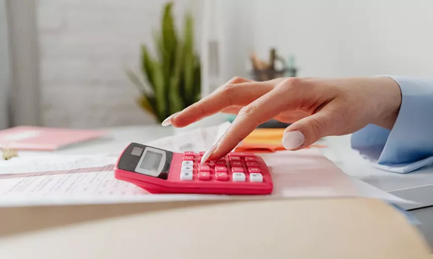 Pessoa utilizando uma calculadora para analisar despesas e renda durante a avaliação financeira do Jobseeker’s Allowance na Irlanda.