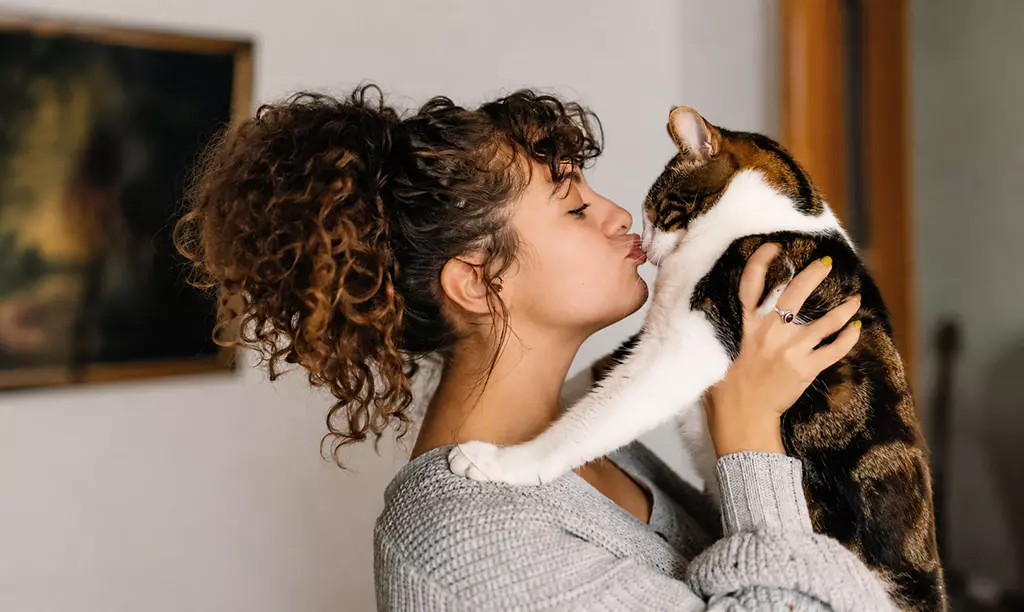 Mulher segurando e acariciando um gato dentro de casa, representando a convivência com pets na Irlanda.