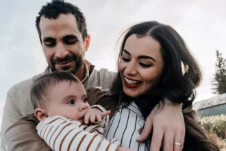 Casal com um bebê em momento de convivência familiar ao ar livre, representando a reunificação familiar na Irlanda.