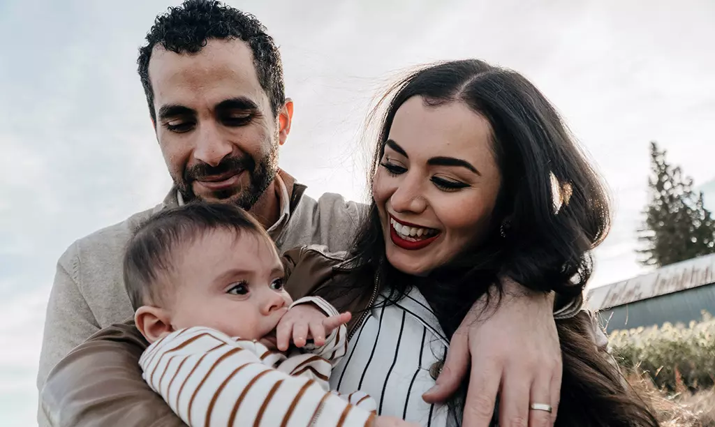 Casal com um bebê em momento de convivência familiar ao ar livre, representando a reunificação familiar na Irlanda.