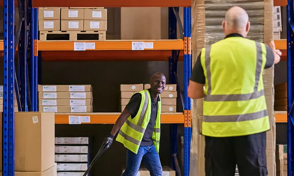 Trabalhadores em um armazém logístico na Irlanda realizando movimentação de mercadorias.